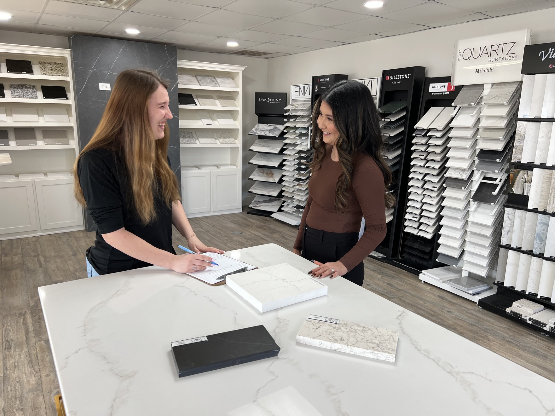 a woman showing another woman a swatch of quartz in a counter showroom